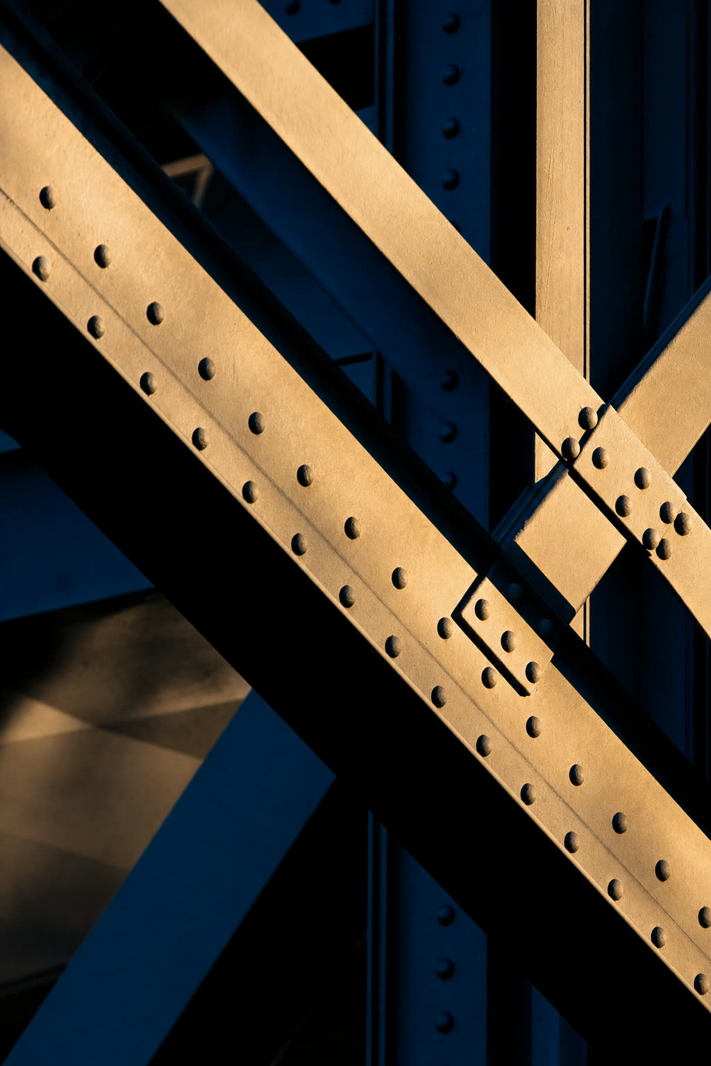 Sunlit steel beams crossing against deep navy shadow