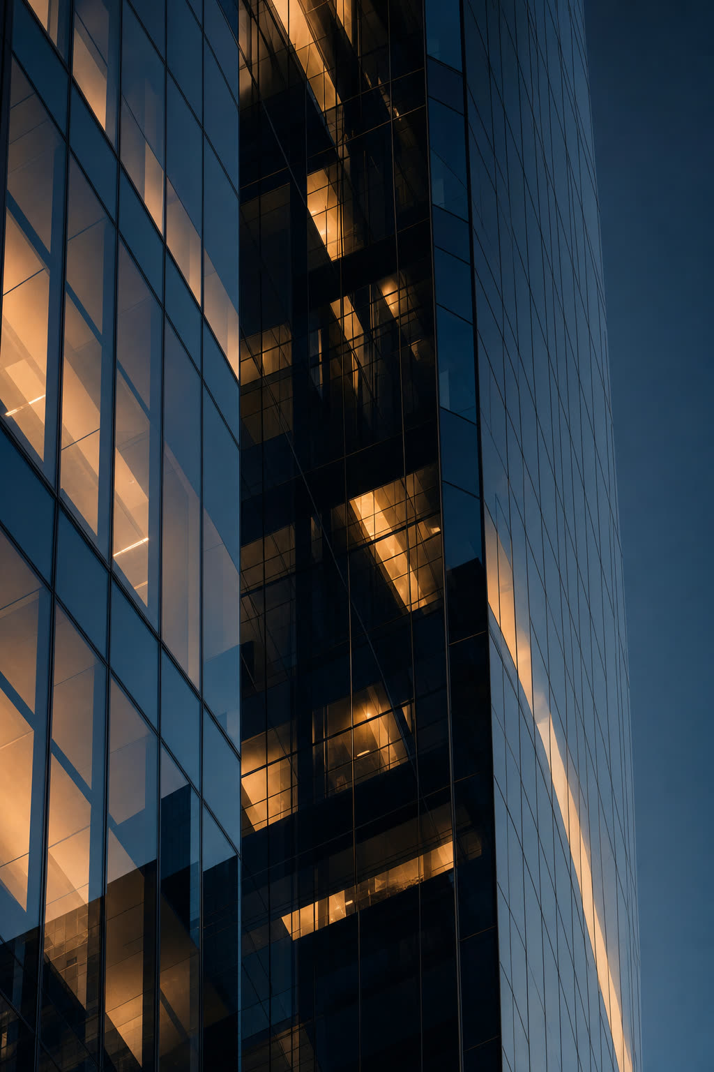Glass-and-steel skyscraper facade reflecting a navy dusk with warm interior glows